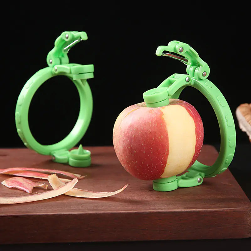 Stainless Steel Fruit Peeler Gadget with green handle peeling a fresh apple on wooden surface with apple peels nearby