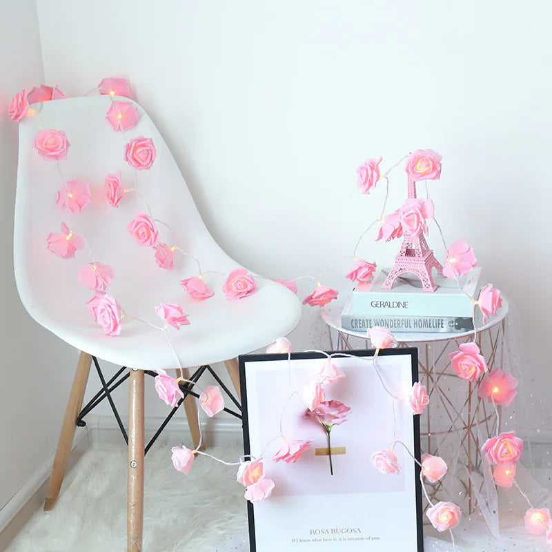 LED Rose Flower String Lights with soft pink rose-shaped bulbs draped over a white chair and decorative table setup