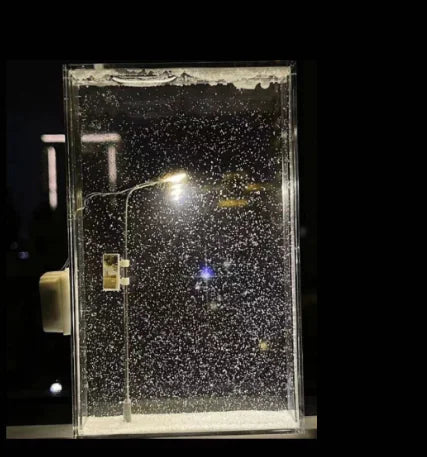 Snow Scene Night Lamp Kit glowing with falling snow effect and illuminated street lamp in a dark setting