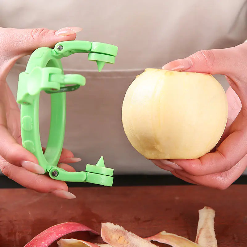 Stainless Steel Fruit Peeler Gadget with green plastic frame peeling an apple held by hands over wooden surface