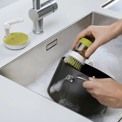 Furniture, Kitchen, and Cleaning Essentials pot dish brush with green handle scrubbing a pan in a soapy kitchen sink