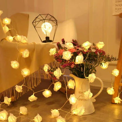 LED Rose Flower String Lights draped over vase with white roses adding warm, soft illumination to cozy room setting